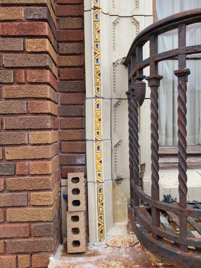 Recast terracotta window frame, with brightly colored geometric pattern, is set into place